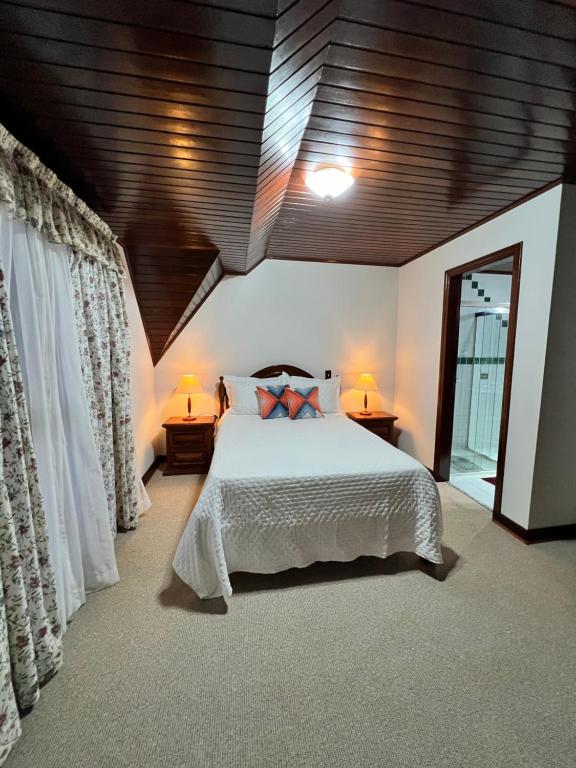 a bedroom with a large bed and two lamps at Vila husky pousada in Campos do Jordão