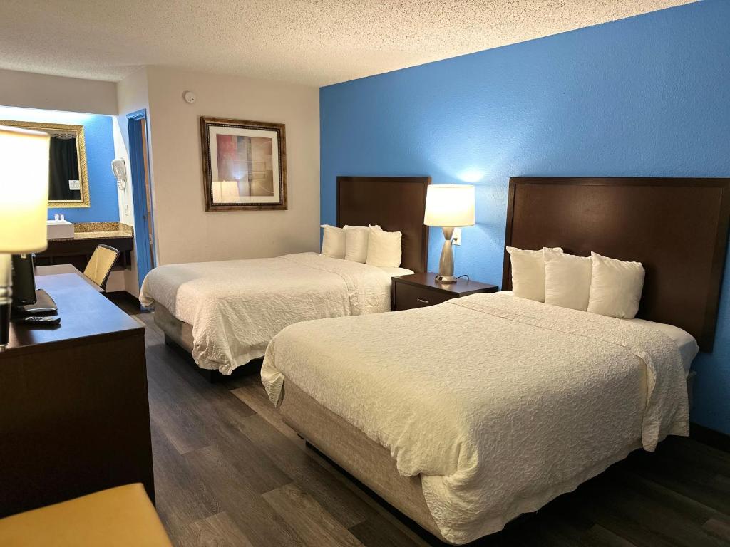 two beds in a hotel room with blue walls at American Inn & Suites Bishop Airport Flint in Flint