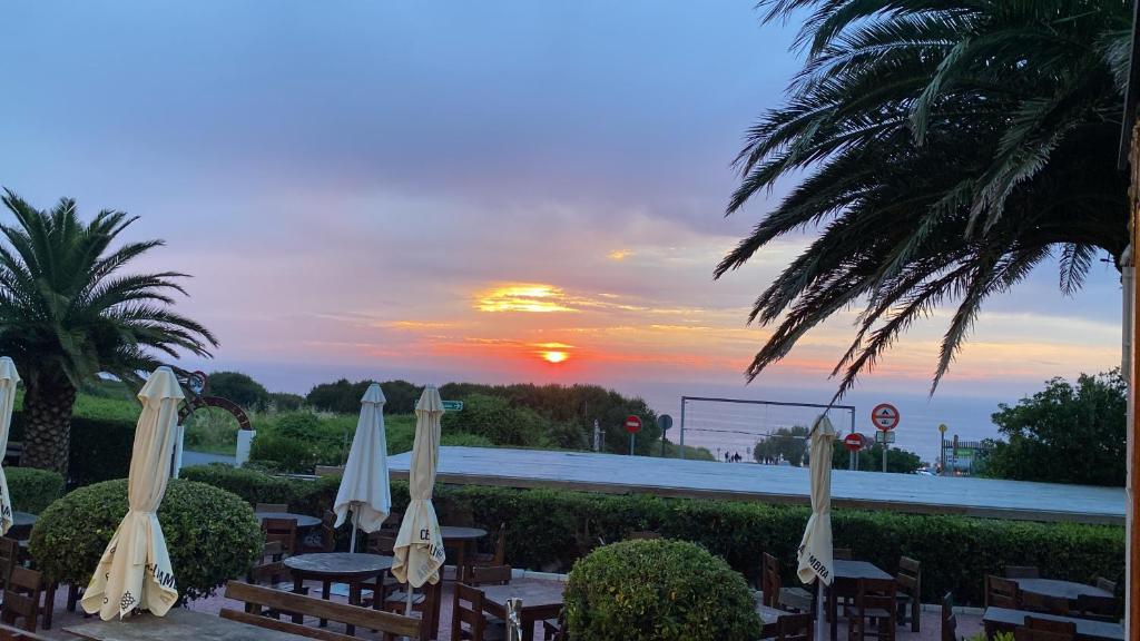 a group of tables with umbrellas in front of a sunset at Tu refugio junto al mar te espera in Elejalde