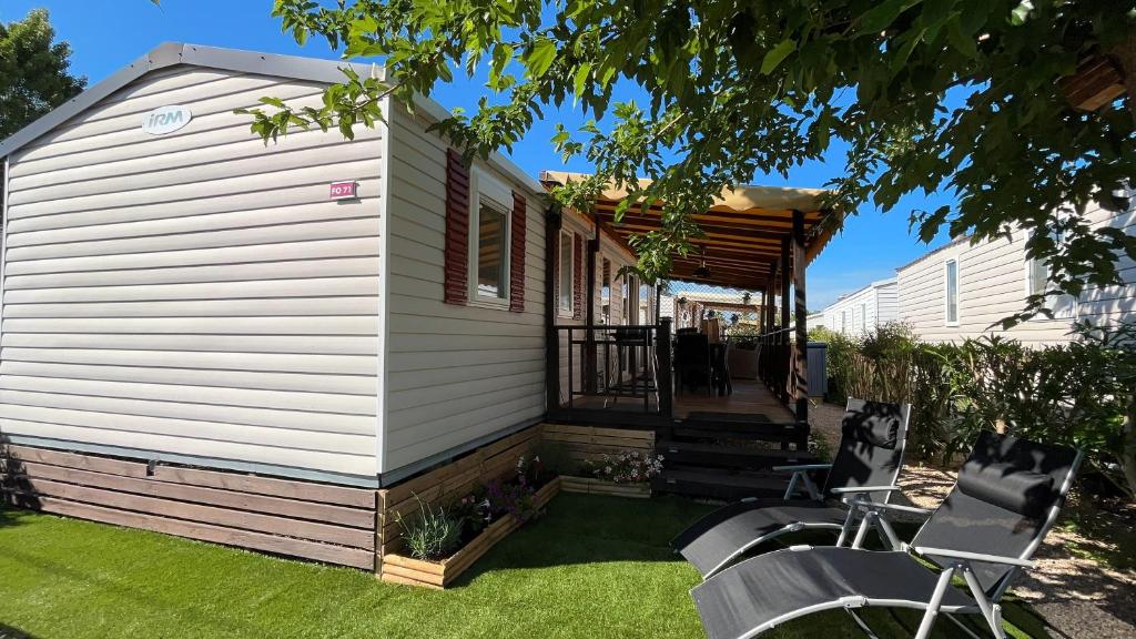 un porche d'une maison avec des chaises sur l'herbe dans l'établissement Fabuleux mobil-homme 4/6 personnes, à Fréjus