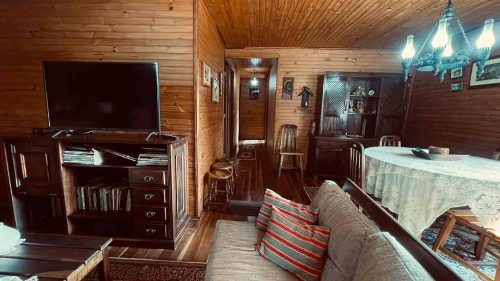 ein Wohnzimmer mit einem Sofa, einem TV und einem Tisch in der Unterkunft Chale em Atibaia in Atibaia