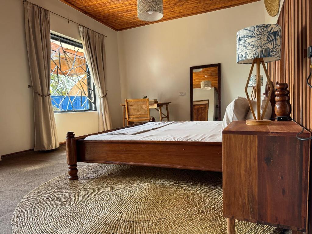 a bedroom with a bed and a lamp and a window at Njombe Cozy House in Njombe