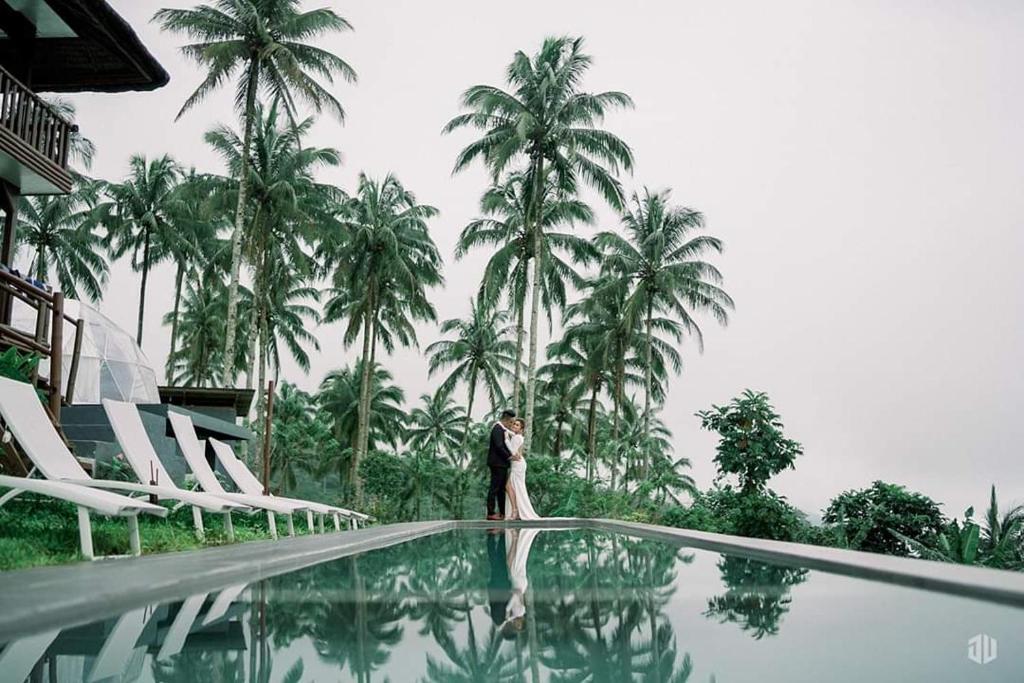 a bride and groom standing on the edge of a swimming pool at Bintana sa Paraiso Binunsaran in Mambajao