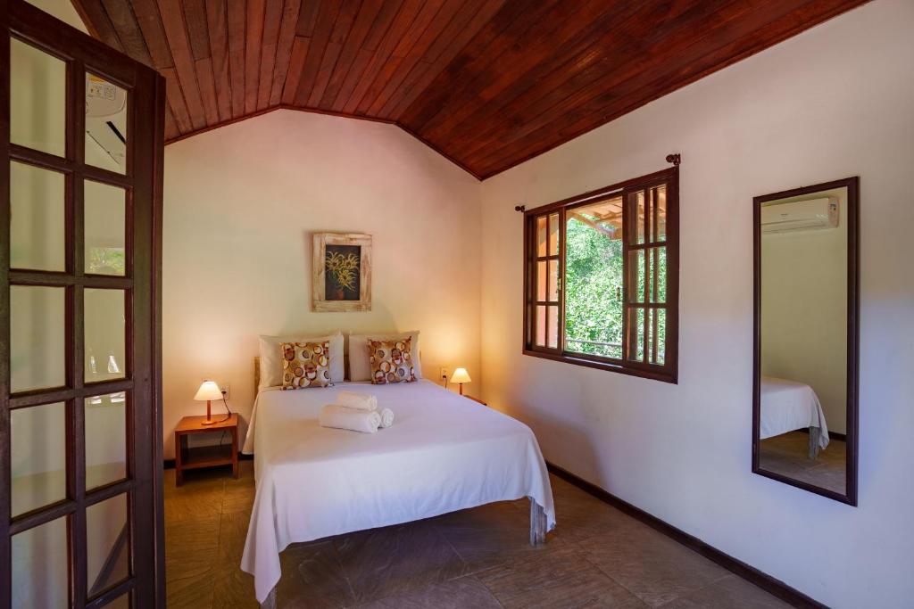 a bedroom with a white bed and a window at Pousada Casa Cactus Praia da Tartaruga Búzios in Búzios