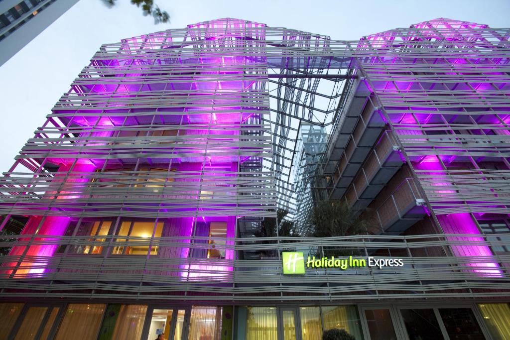 un edificio con luces púrpuras en el lateral. en Holiday Inn Express Paris-Canal De La Villette, an IHG Hotel en París