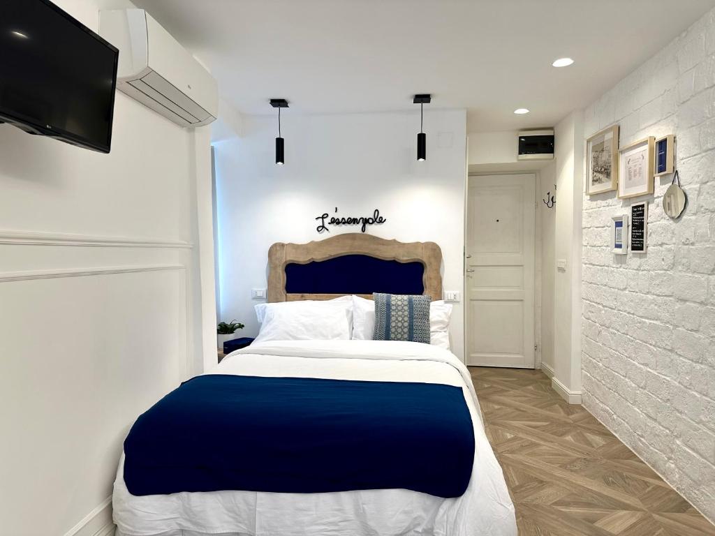 Schlafzimmer mit einem blauen und weißen Bett und einem TV in der Unterkunft L ESSENZIALE a Trieste in Triest