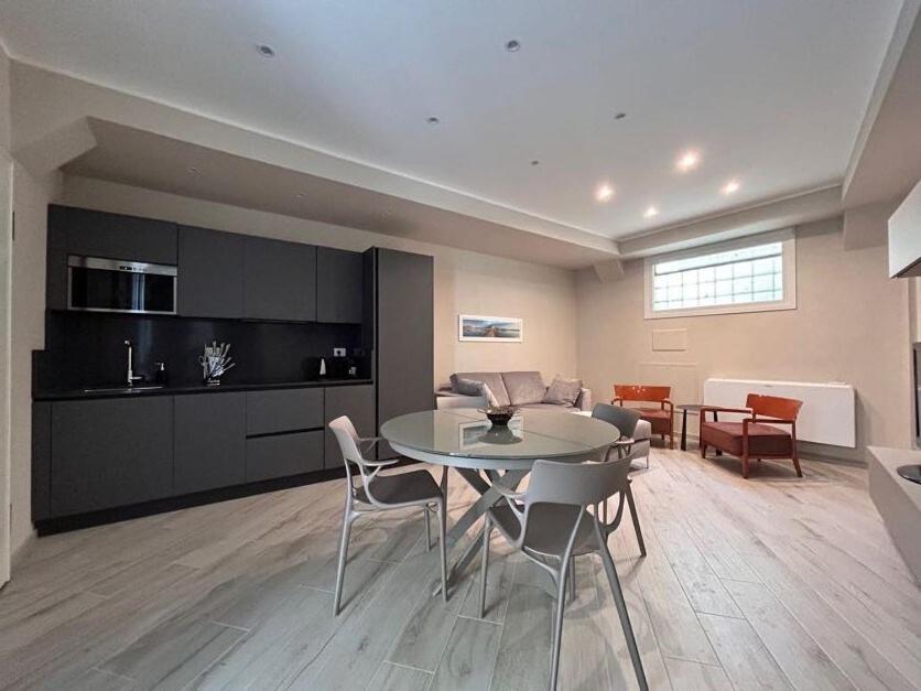a living room with a table and a kitchen at Homeby, Modern Loft Pisa in Pisa