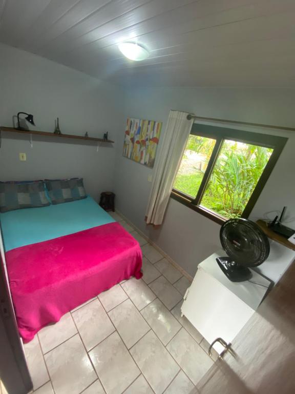 a bedroom with a red bed and a window at Rancho Caiçara in São Francisco do Sul