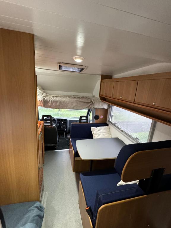 Camping Van في كيفلافيك: غرفة صغيرة مع طاولات وكراسي في سيارة أجرة