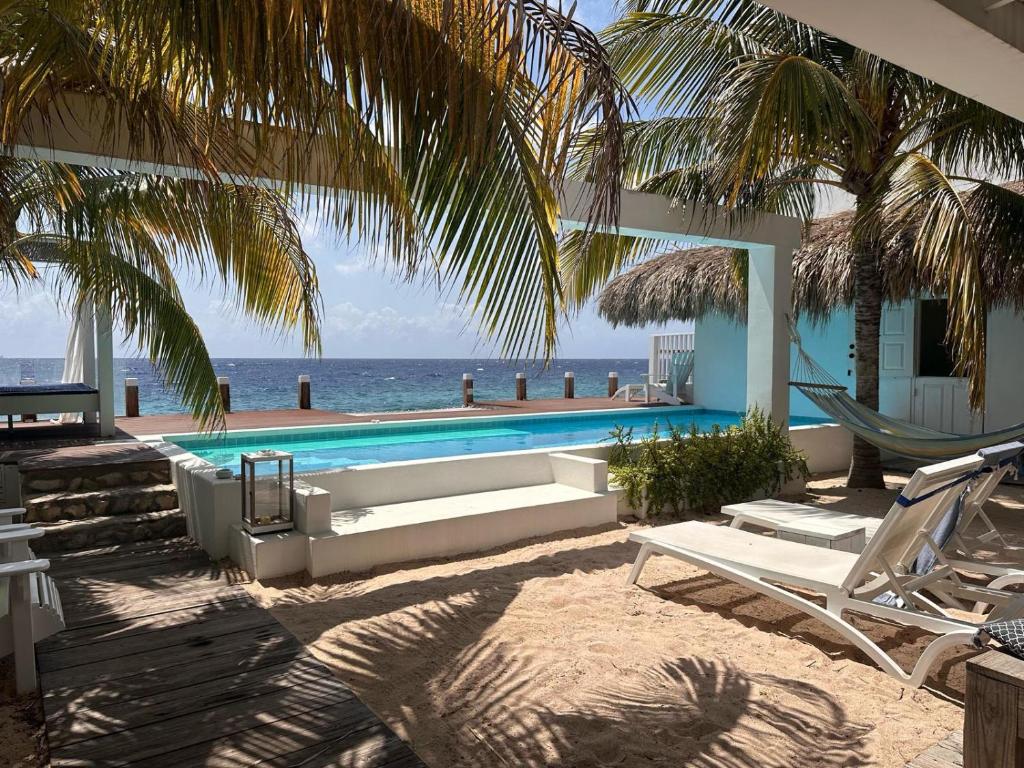 a resort with a swimming pool and chairs and the ocean at Beach House Pietermaai in Historic Pietermaai District in Willemstad