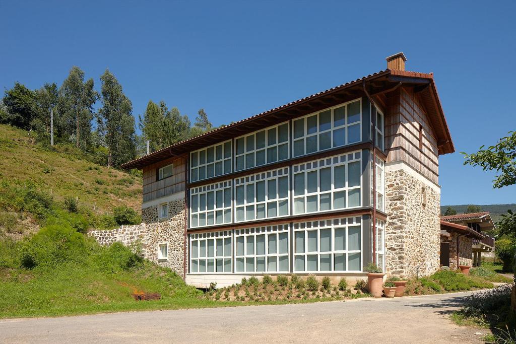 un gran edificio con ventanas en un lateral de una colina en Ureta Landa Gaztelugatxe, en Bakio