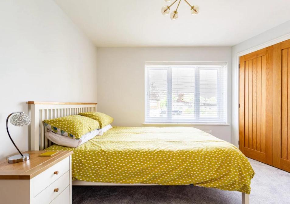 um quarto com uma cama com lençóis amarelos e uma janela em Whiteclouds em Cheshunt