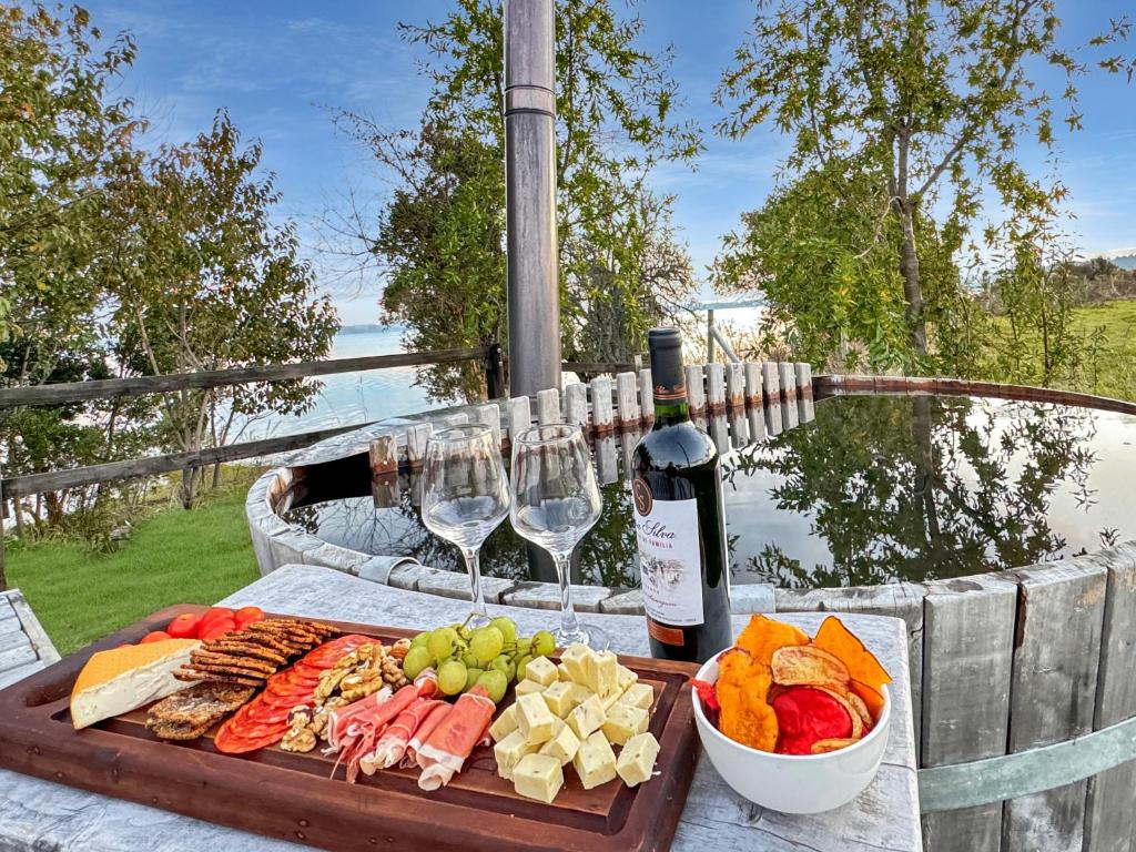 una mesa con una bandeja de comida y copas de vino en Orilla de Lago con Hot Tub, parrilla y vistas en Puyehue