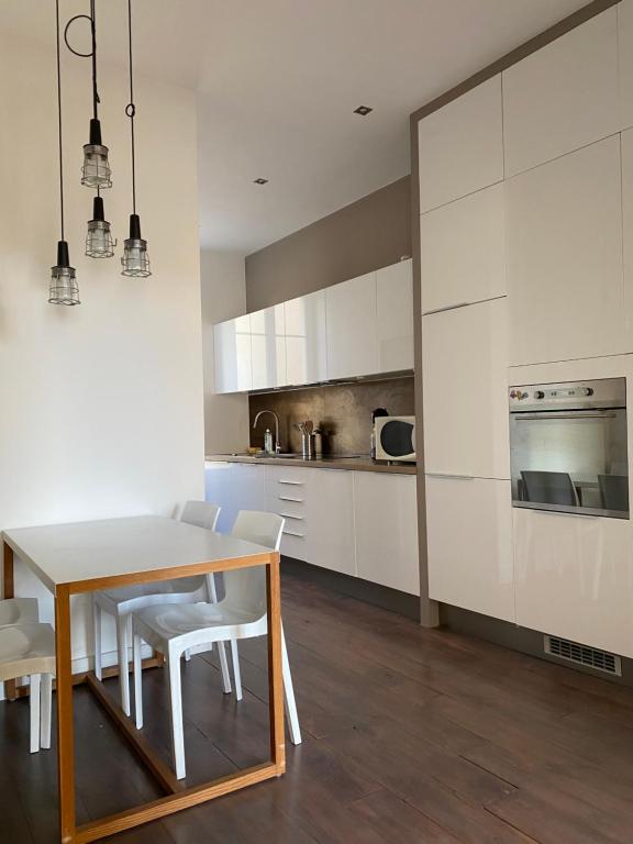 une cuisine avec des armoires blanches et une table et des chaises dans l'établissement Cozy Apartment Nice Valrose, à Nice