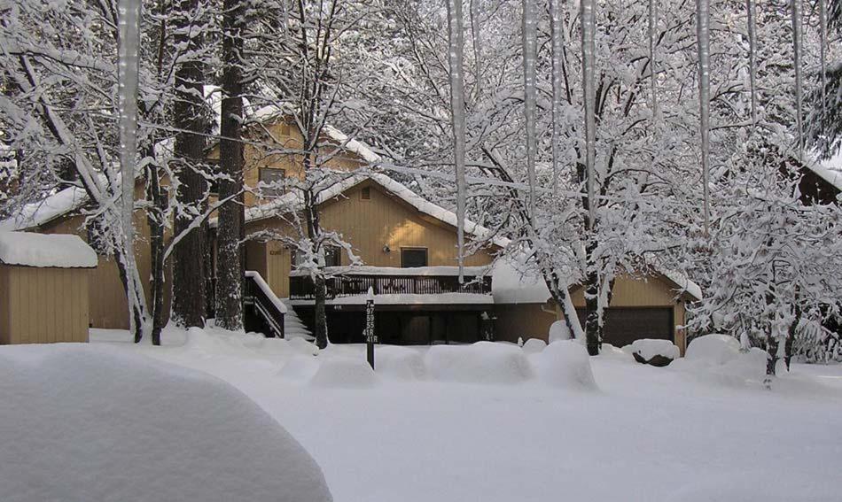 a house covered in snow in front of trees at Wawona Home in Wawona
