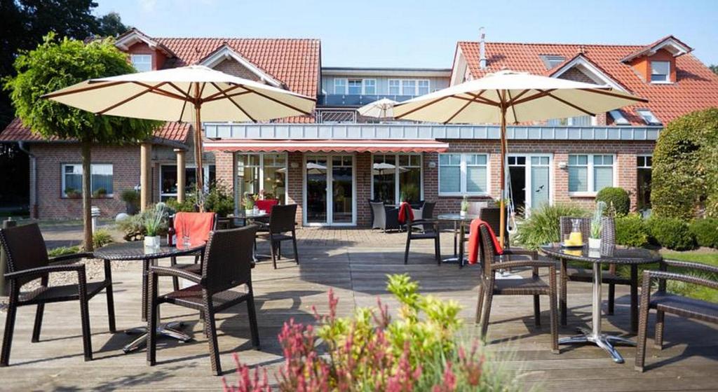 eine Terrasse mit Tischen, Stühlen und Sonnenschirmen in der Unterkunft Hotel Waldblick Deppe in Lippstadt