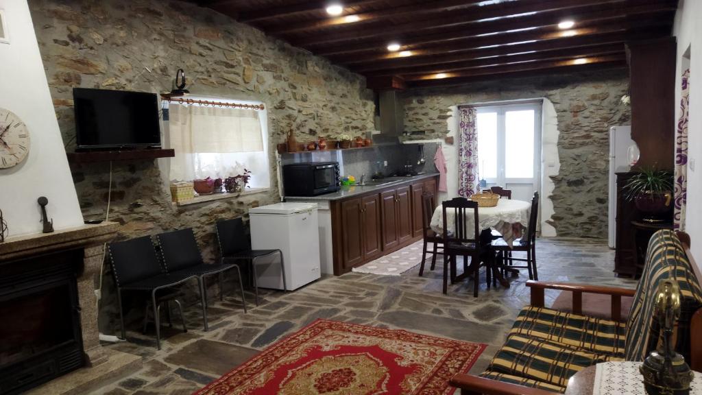 a kitchen with a stone wall and a table and chairs at O Recanto do Sobreiro in Vale de Porco