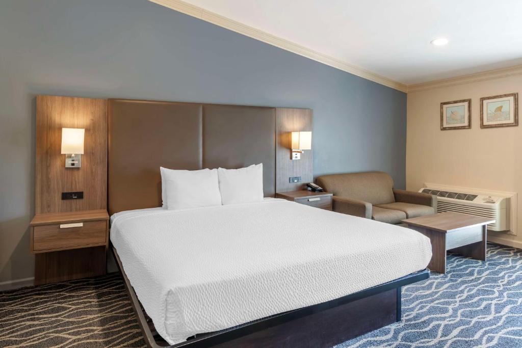 a hotel room with a large bed and a chair at Best Western Plus Hill House in Bakersfield