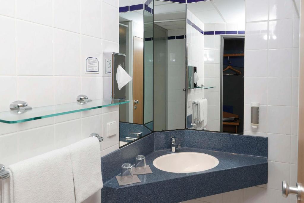 ein Bad mit einem Waschbecken und einem Spiegel in der Unterkunft Median Hotel Hannover Messe in Hannover