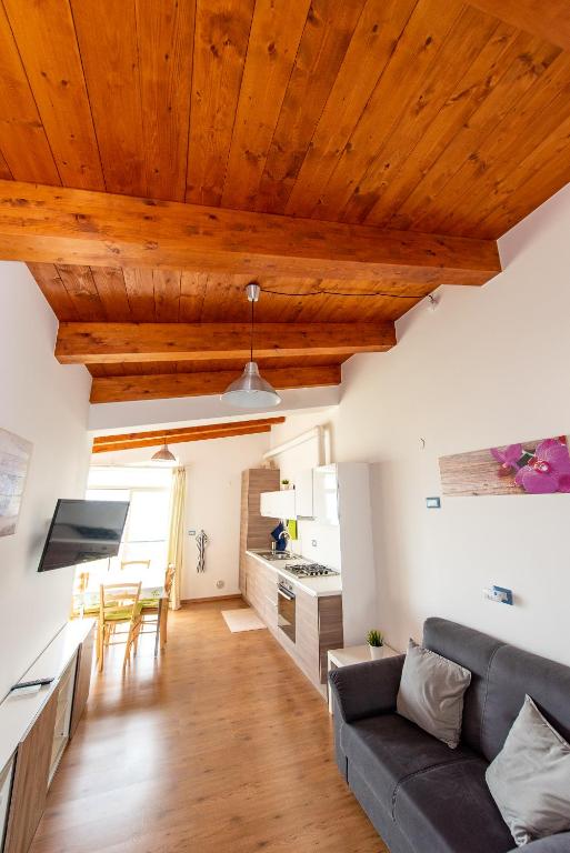a living room with a gray couch and wooden ceilings at Appartamenti Adriatico & Gran Sasso in Pineto