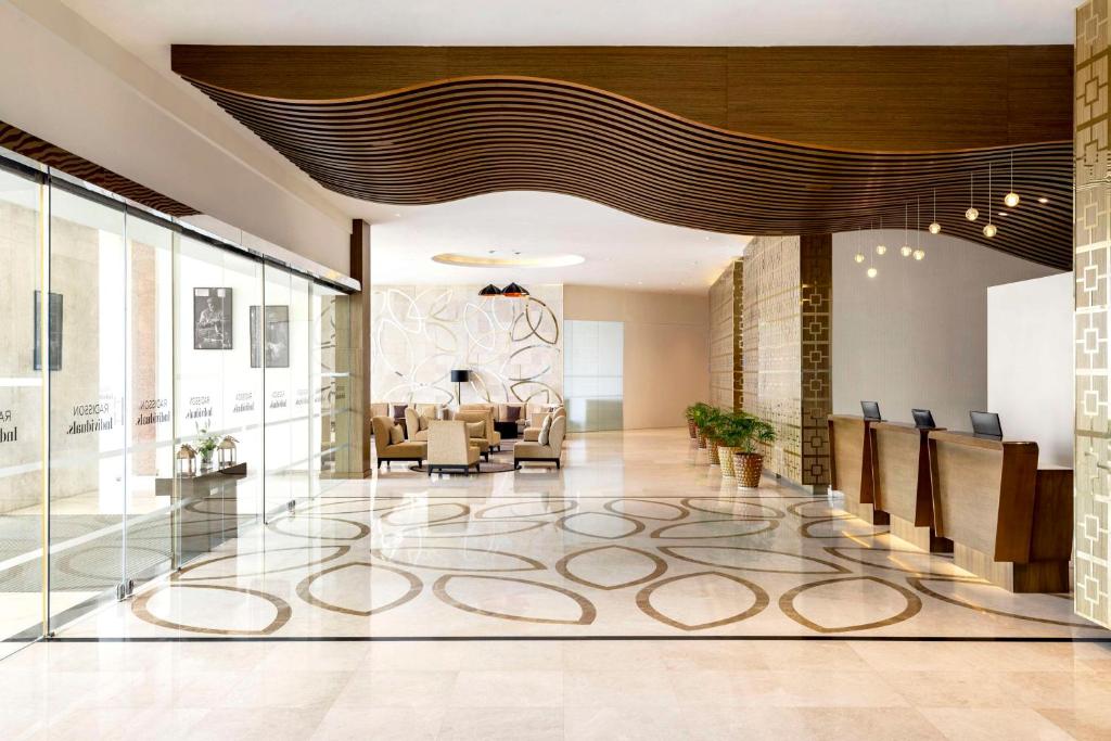 un vestíbulo con una zona de espera con sillas y mesas en Levatio Suites Muscat, a member of Radisson Individuals, en Mascate