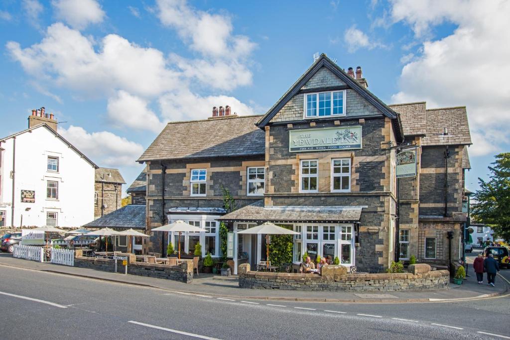 an old stone building with umbrellas on a street at The Yewdale Inn and Hotel Coniston Village in Coniston