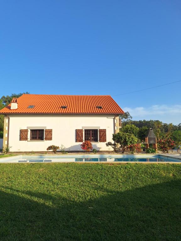 a white house with a red roof and a swimming pool at LIMA COTTAGES - Casa de S Tiago in Ponte de Lima