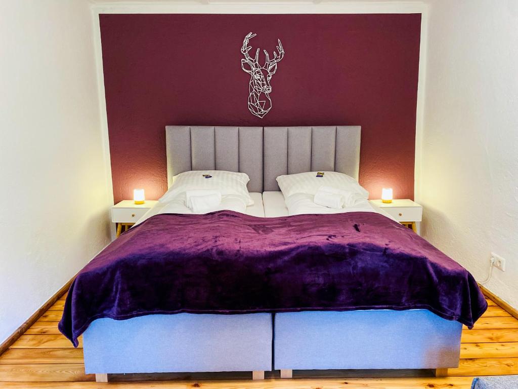 ein Schlafzimmer mit einem großen Bett mit violetter Bettwäsche und zwei Lampen in der Unterkunft Belisima Apartments I Ferienwohnungen Fischbachau - Breitenstein I Region Schliersee I Historisch & Cozy mit Bergblick I 2 Schlafzimmer I Waschmaschine I Parkplatz I Nähe Supermarkt in Fischbachau