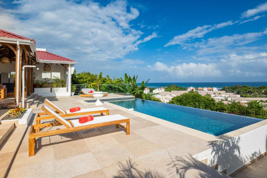 an image of a villa with a swimming pool at Résidence Les Raisins Clairs - Villas standing 4 étoiles , vue sur mer panoramique & piscine à débordement in Saint-François