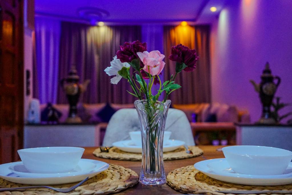 wazon kwiatów siedzący na stole z talerzami w obiekcie IDGA appartement with panoramic view w mieście Szafszawan