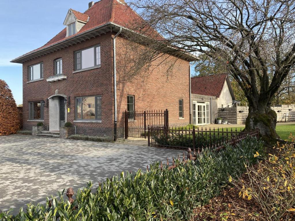 une grande maison en briques avec un arbre en face de celle-ci dans l'établissement Het Bruegelhof, à Peer