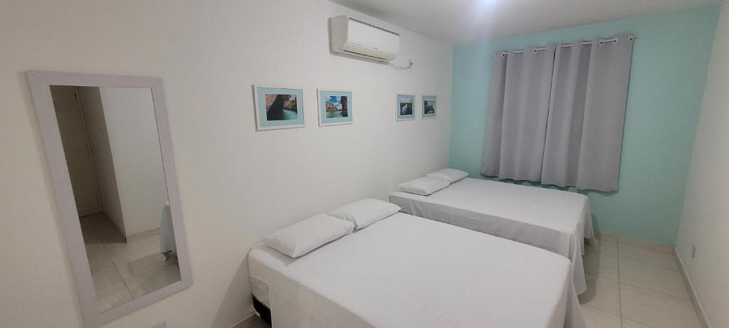 ein weißes Zimmer mit 2 Betten und einem Spiegel in der Unterkunft Aquarela do Sertão in Piranhas