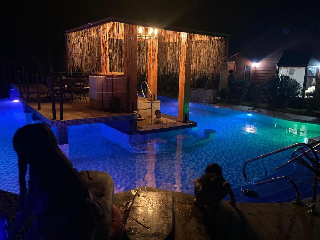 una piscina por la noche con gente en el agua en Hotel Boutique Family Suites, en Panguipulli