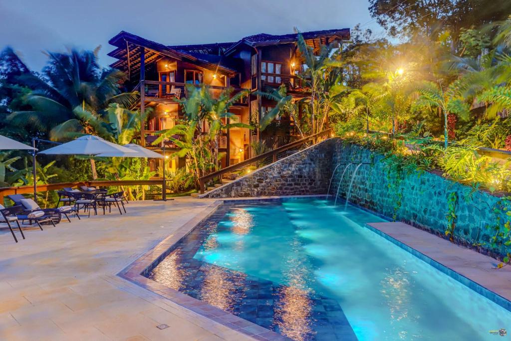 uma piscina em frente a uma casa à noite em Chocolate Hotel em Itacaré