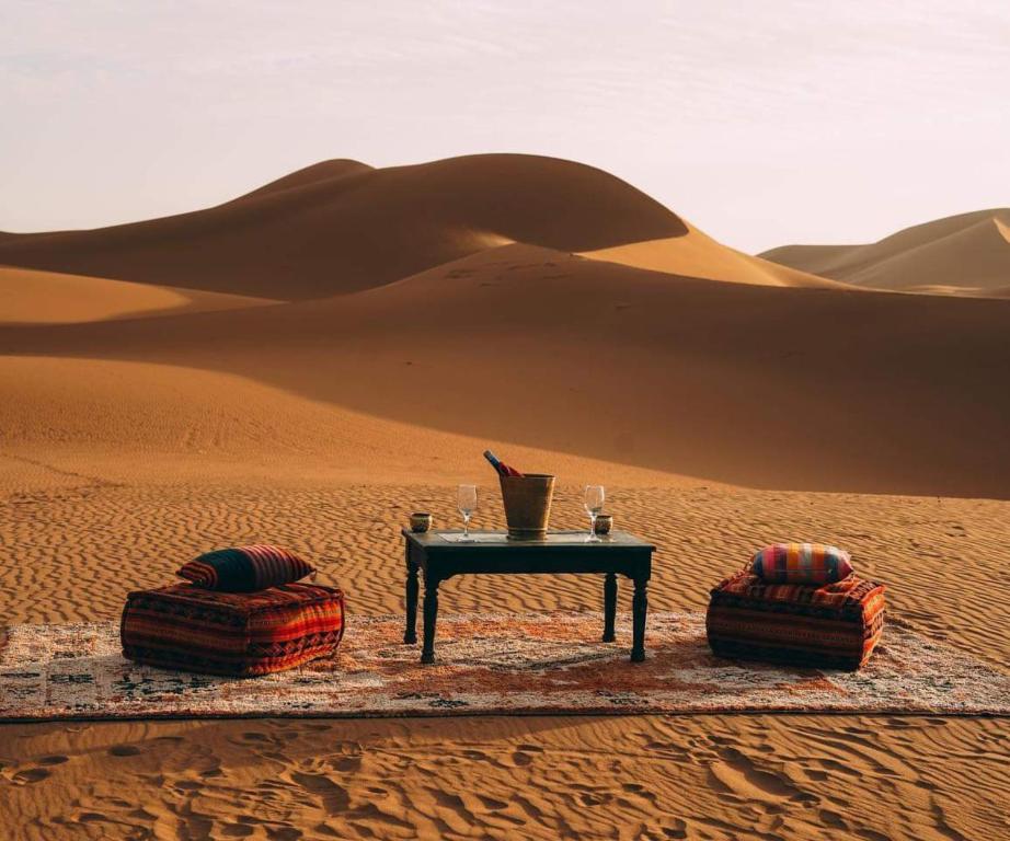 a table in the middle of the desert with two pillows at Mhamid Tours in Mhamid
