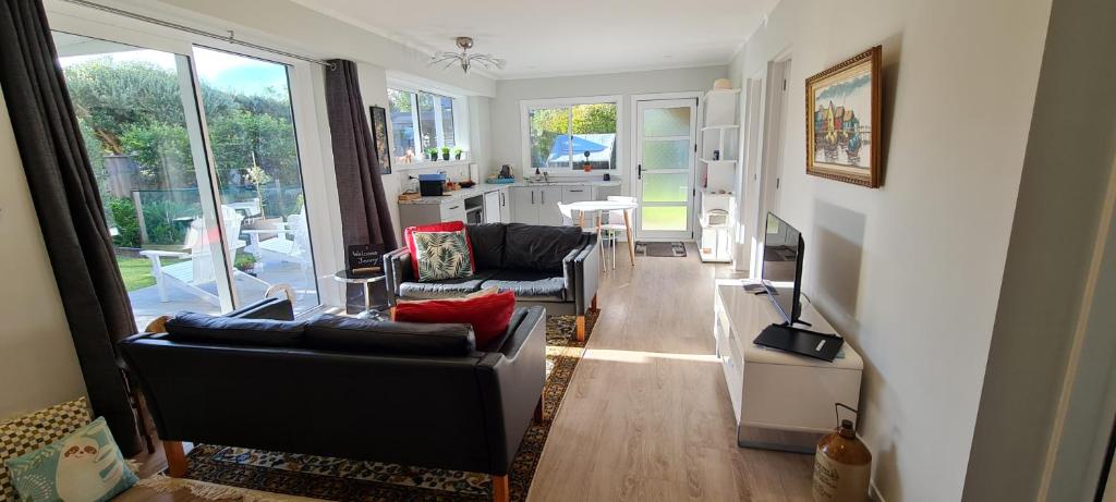 a living room with two couches and a kitchen at Waikanae Beach Suite Retreat in Waikanae