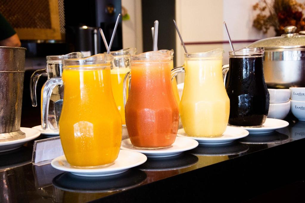 a group of four glasses of juice on a counter at Athos Hotel in Teresópolis
