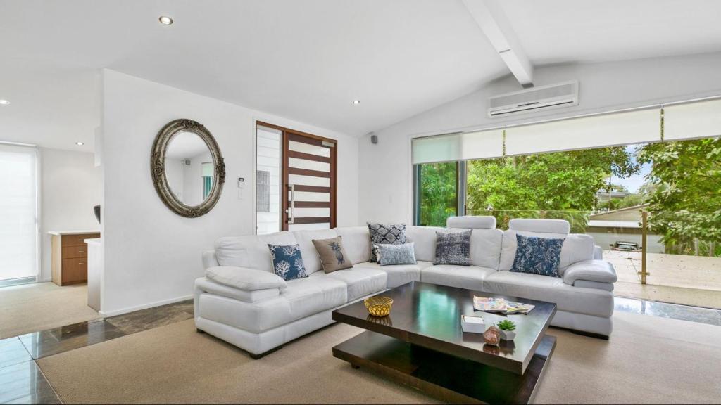 uma sala de estar com um sofá branco e uma mesa em 9 Depper St - Upper Level Only em Sunshine Beach