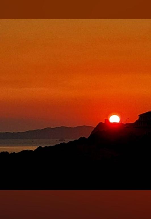 a sunset with the sun setting on a mountain at Angelos aparts in Arillas