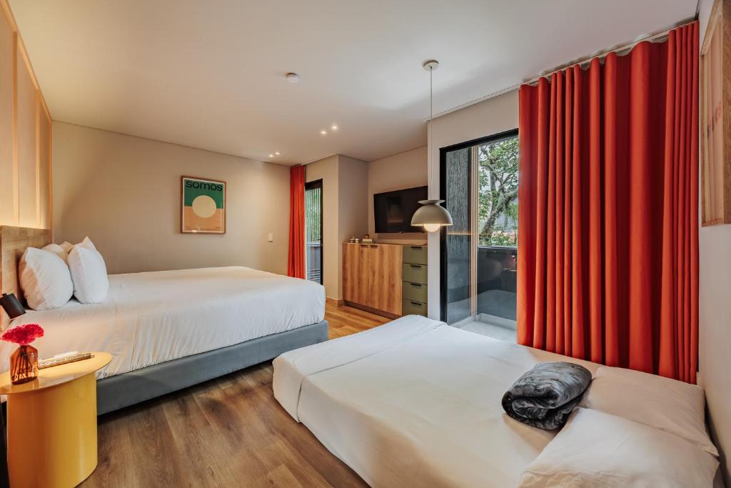 a hotel room with two beds and a window at The Somos Central Hotel Poblado in Medellín