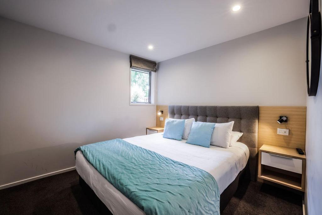 a bedroom with a large bed with blue pillows at Tasman Holiday Parks - Te Anau in Te Anau
