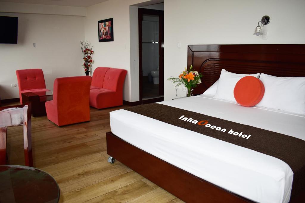 Habitación de hotel con cama y sillas rojas en InkaOcean Hotel, en Ilo