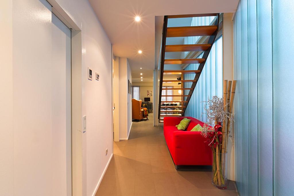 a hallway with a red couch and a staircase at Casa Soto Del Ebro in Tudela