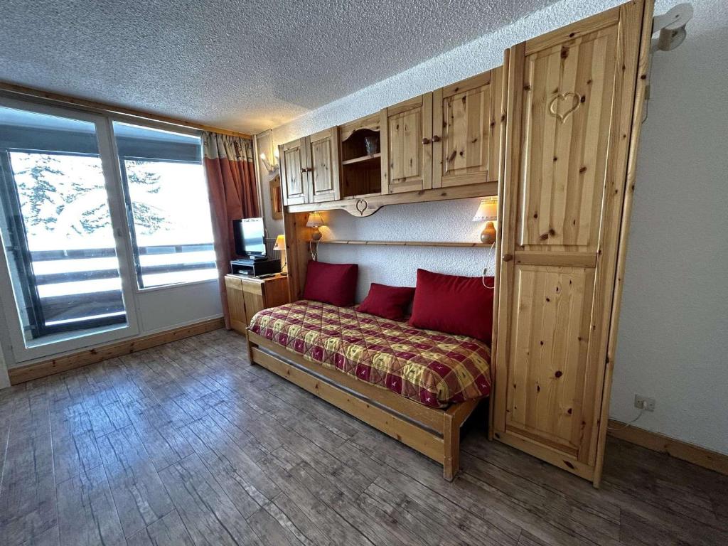 une chambre avec un lit avec des oreillers rouges dans l'établissement Studio confortable pour 4 avec vue pistes, Ski-in/Ski-out - FR-1-452-356, aux Menuires