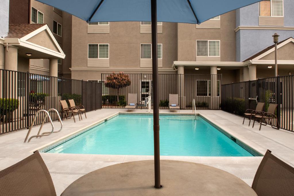 uma piscina com um guarda-sol em frente a um edifício em TownePlace Suites Sacramento Cal Expo em Sacramento