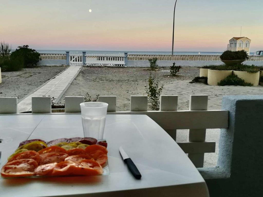 une assiette de pizza sur une table à côté de la plage dans l'établissement Appartement rénové 2 pièces 4 pers avec jardin privatif - Plage à 2 pas - Port-la-Nouvelle - FR-1-229C-95, à Port-la-Nouvelle