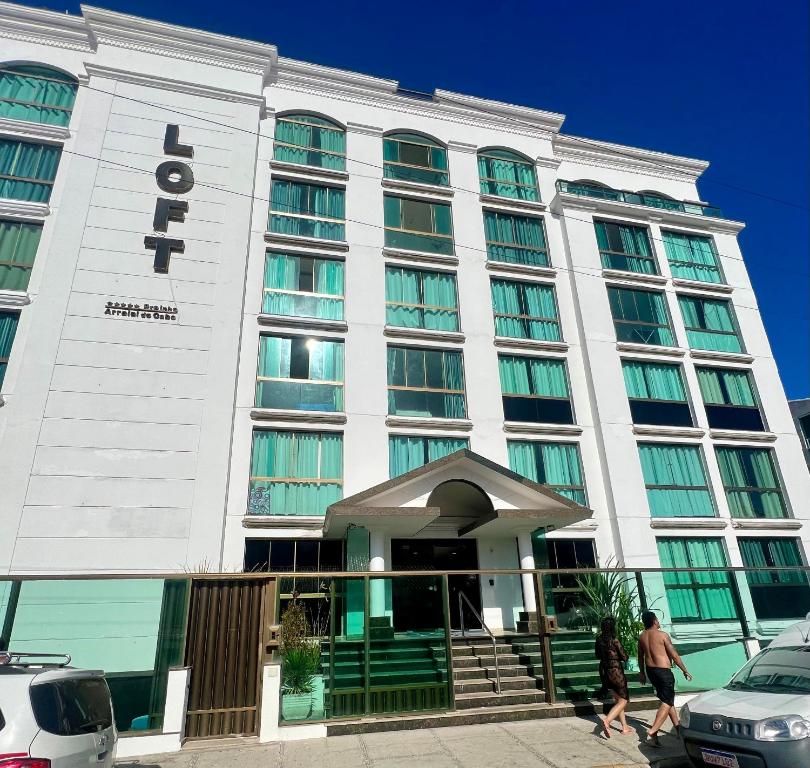 two people walking in front of a hotel at Loft Prainha 101, arraial do cabo in Arraial do Cabo