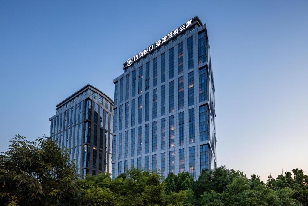 dos edificios altos con árboles delante de ellos en CM Service Apartment Tianjin, en Tianjin