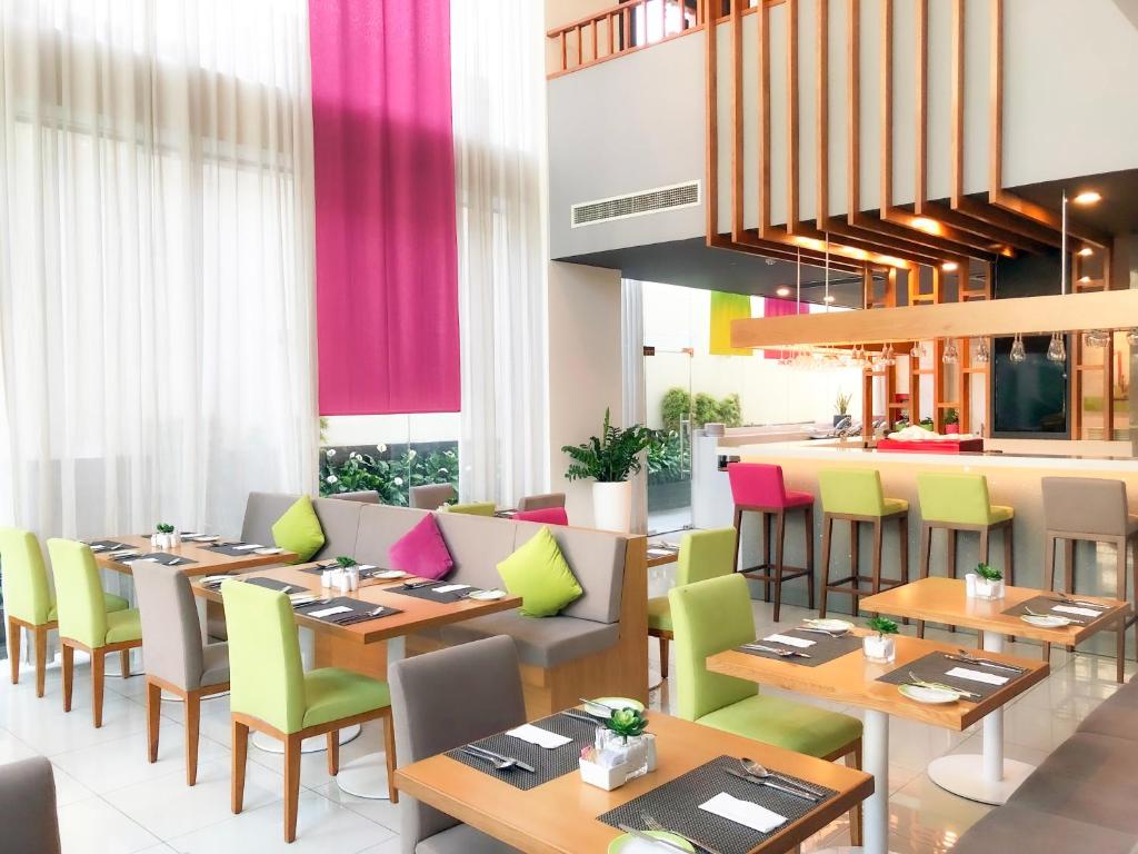 um restaurante com mesas de madeira e cadeiras coloridas em ÊMM Hotel Saigon em Ho Chi Minh