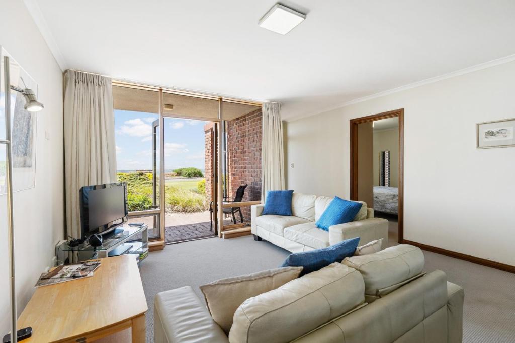 a living room with a couch and a tv at By The Sea Beachfront Apartment Wifi in Encounter Bay